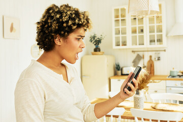 Side view of upset shocked black girl, frustrated with discharged phone interrupting stream or online show, holding smartphone in front of her, screaming looking at black phone screen