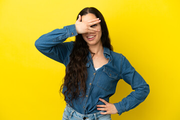 Young caucasian woman isolated on yellow background covering eyes by hands and smiling