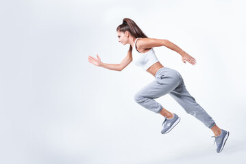 Fototapeta na wymiar Sports woman runner on a white background. Photo of an attractive woman in fashionable sportswear. Dynamic movement. Side view. Sports and healthy lifestyle