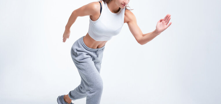 No name portrait. Sports woman runner on a white background. Photo of an attractive woman in fashionable sportswear. Dynamic movement. Side view. Sports and healthy lifestyle.