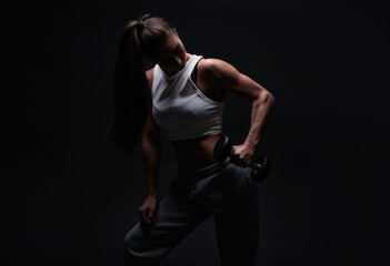 Fototapeta na wymiar Athletic fitness woman posing in the studio on a dark background. Photo of an attractive woman in fashionable sportswear. Sports and healthy lifestyle