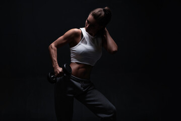 Fototapeta na wymiar Athletic fitness woman posing in the studio on a dark background. Photo of an attractive woman in fashionable sportswear. Sports and healthy lifestyle