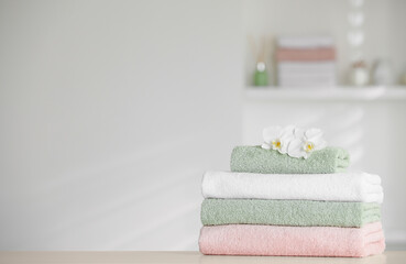 Obraz na płótnie Canvas Stack of clean soft towels with orchid flowers on white table indoors. Space for text