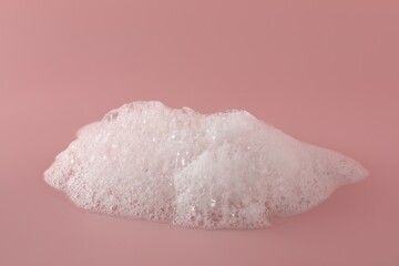 Fluffy bath foam on pink background, closeup. Care product