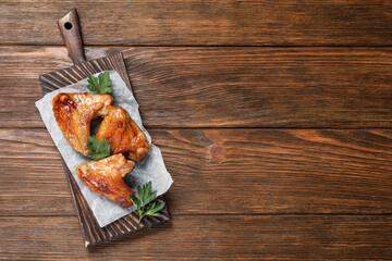 Fototapeta na wymiar Delicious fried chicken wings on wooden table, top view. Space for text