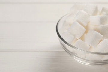 Bowl with sugar cubes on white wooden table. Space for text