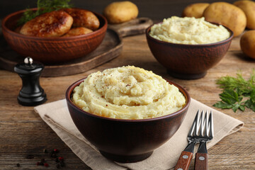 Bowl of tasty mashed potatoes with black pepper served on wooden table