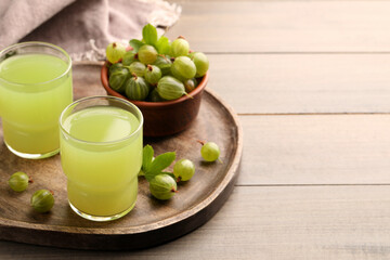 Tasty gooseberry juice and fresh berries on wooden table. Space for text