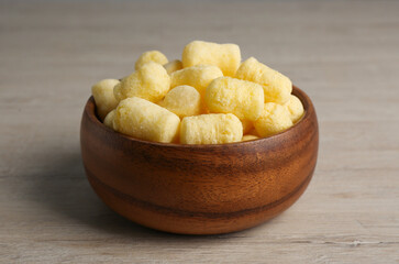 Bowl of corn sticks on wooden table, closeup