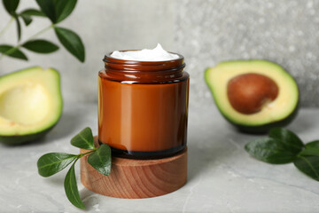 Jar of face cream and avocado on marble table