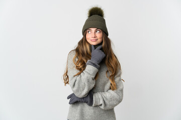 Young caucasian woman with winter hat isolated on white background having doubts