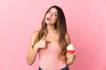 Young caucasian woman with a cornet ice cream isolated on pink background with surprise facial expression