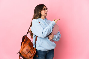Young student woman isolated on pink background pointing finger to the side and presenting a product