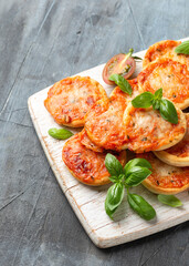 Mini pizzas with tomatoes and mozzarella cheese on white wooden board
