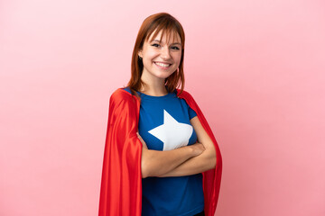 Super Hero redhead girl isolated on pink background with arms crossed and looking forward