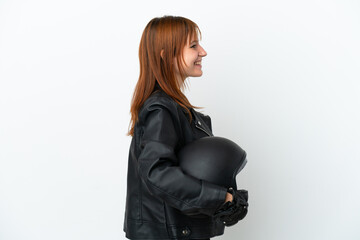 Redhead girl with a motorcycle helmet isolated on white background laughing in lateral position