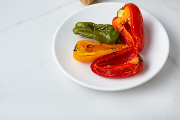 Close up of sliced roasted red yellow bell pepper on plate vegan food