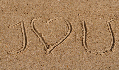 Close up on a message hand drawn in the sand of  a beach saying 