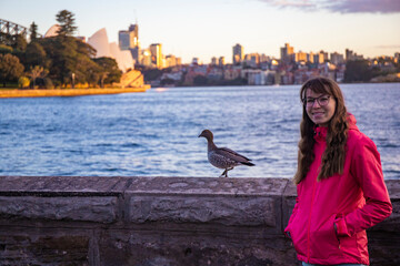 beautiful girl and a wild duck with famous sydney opera house in background; sunrise over sydney...