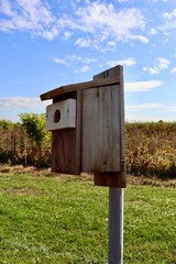A close view of the old box wood birdhouse in the field.