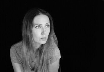 A woman on a black background looks into the distance there is a place for an inscription
