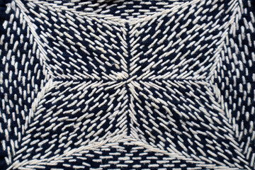 White thread sew on dark blue cloth fabric textile background. Hand embroidery is the art of decorative stitching on fabric with needle and thread.