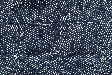 White thread sew on dark blue cloth fabric textile background. Hand embroidery is the art of decorative stitching on fabric with needle and thread.