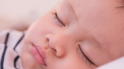 Close-up portrait of eye lash in baby face asian sleeping on bed. While cute newborn baby asleep in bedroom. Innocent little new infant adorable. Parenthood and Mother Day concept.