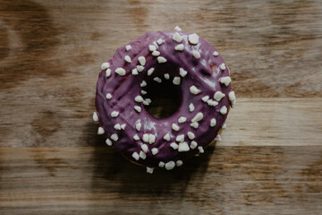 donuts color morado con azucar y chocolate encima de una tabla de madera en vista cenital