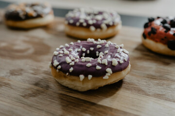 conjunto de donuts de diferentes colores con chocolate y azúcar encima de una tabla de madera