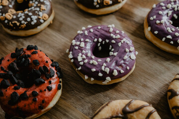 conjunto de donuts de diferentes colores con chocolate y azúcar encima de una tabla de madera