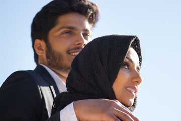 Side view of young romantic couple. Attractive Muslim woman in black headscarf and handsome...