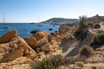 Beautiful shoreline on Gozo, Malta with boats anchored. Summer weather with clear blue sky.