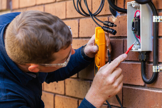 Electrician using multimeter tool to check power in solar system installation