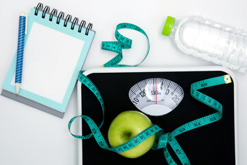 Weight scale and measure tape with green fresh apple , Healthy diet for weight loss control concept , blank copy space on a page of spiral notepad paper for text - 538599793
