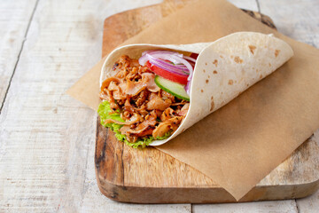 doner donair kebab wrap with spicy meat, lettuce, tomato, red onion. Served on wooden cutting...