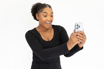 Portrait of happy young woman taking selfie with smartphone. African American lady wearing black longsleeve posing for photo and smiling against white background. Social networking concept