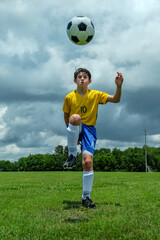 Action shot of a young soccer player kicking soccer ball into the air