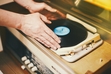 Istra, Russia - September 06, 2021: Vinyl record, spinning on turntable, Vintage record player with radio 60's. Mens hands putting vintage record in vinyl player