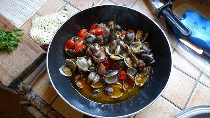 A pan with clams, garlic, fresh tomatoes and extra virgin olive oil ready for the dish.