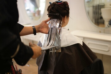 Obraz na płótnie Canvas 女性の髪のカラーリングをする男性美容師