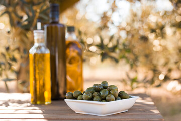 green olives and oil on table in olive grove