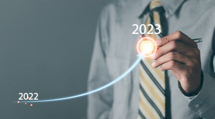 Businessman holding down arrow graphing growth from 2022 to 2023 of business and data analysis. Successful development in 2023