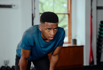 Fototapeta na wymiar Focused young black man in sportswear taking a break at the gym