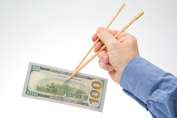 hand holds dollars with bamboo chopsticks on a white background. financial industry in food. cash spending concept