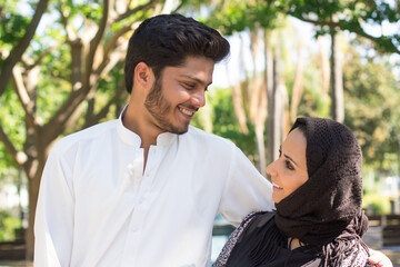Fototapeta premium Close-up of happy romantic Arabian couple. Young handsome man and beautiful woman standing close smiling looking at each other with love. Romance, dating and relationship concept