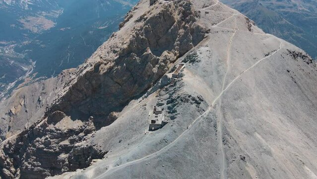 aerial scenic view of ruined artillery batteries with people (515a Batteria Guardia alla Frontiera), Mont Chaberton peak. Mont Rochebrune peak in background