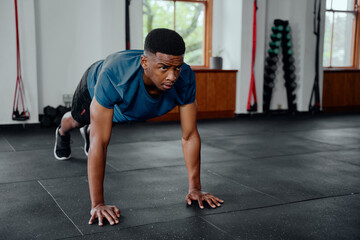 Fototapeta na wymiar Fit young black man doing push-ups at the gym