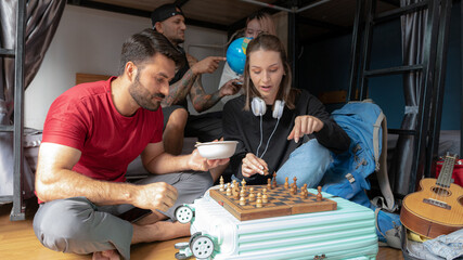 Groups of travelers of different nationalities having fun in the hostel.