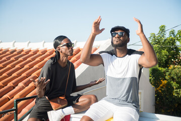 Portrait of young African gay couple concentrated on talk. Two thoughtful bearded men sitting together on bench talking making gestures with their hands. LGBT couples happiness and lifestyle concept